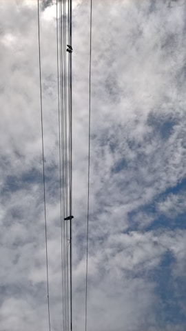 Several power lines stretch vertically against a backdrop of a cloudy sky. The clouds vary in density and the sky appears partly cloudy with hints of blue visible through the gaps.