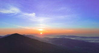 A vibrant photo of a happy traveler looking out over a scenic mountain vista at sunrise.