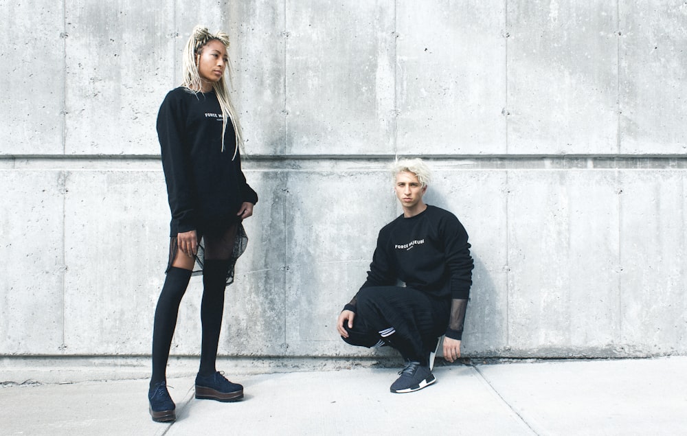 man kneeling and woman standing near wall