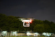 Nighttime flight of a drone with illuminated sensors mapping an outdoor environment.