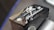A close-up of a motorcycle part with embossed text and symbols. The text 'Hayabusa' is prominently featured alongside a stylized Japanese character. The part has a metallic, angular design with a black finish and highlights visible on its surface.