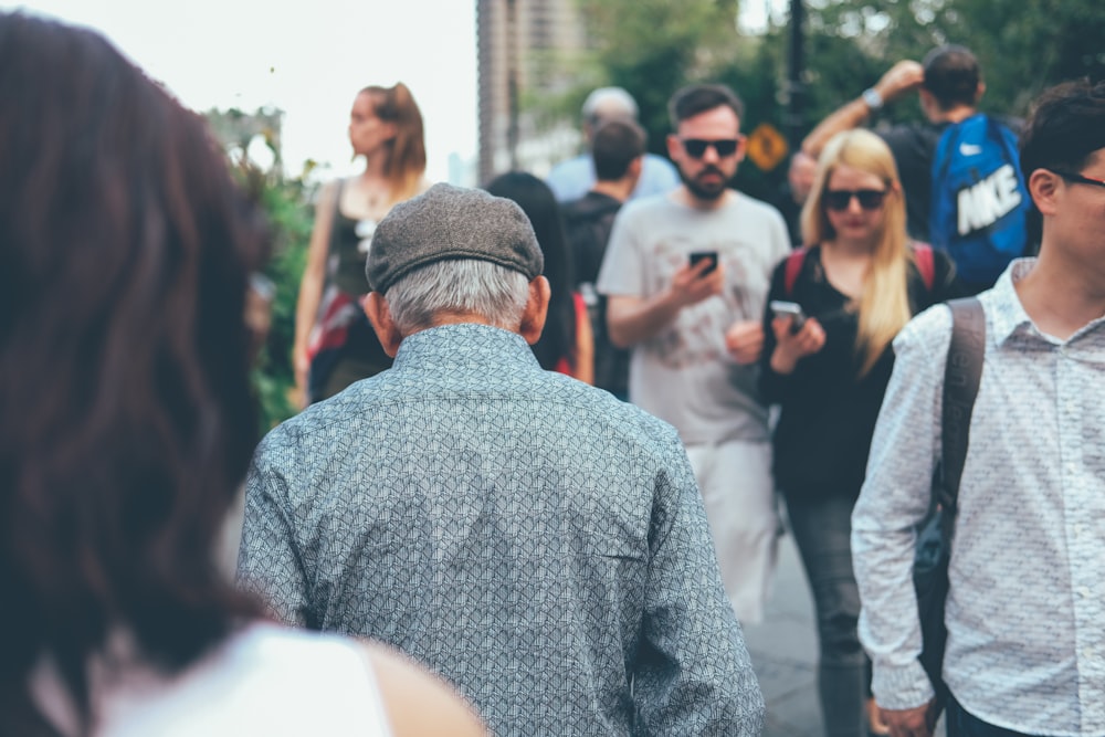 homme portant une chemise à col turquoise marchant à travers un couple de personnes