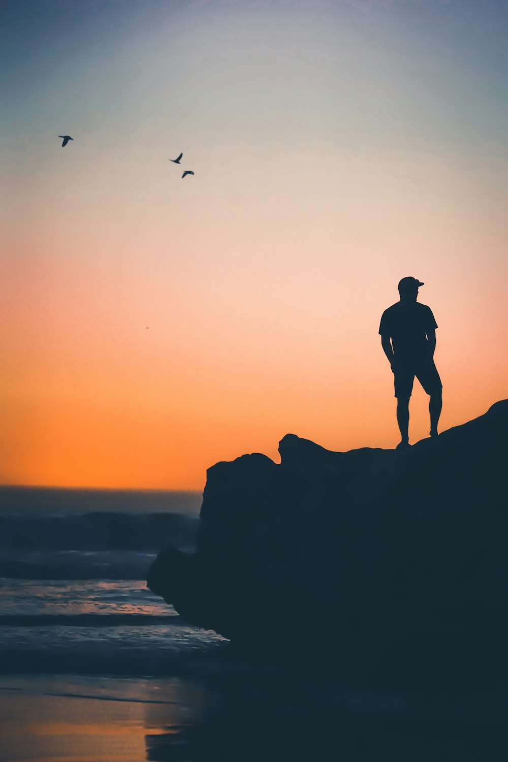 hombre de pie en la roca cerca de la orilla del mar