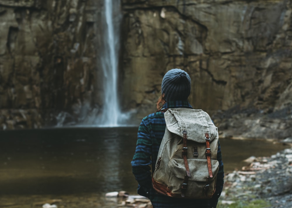 woman with backpack facing waterfalls