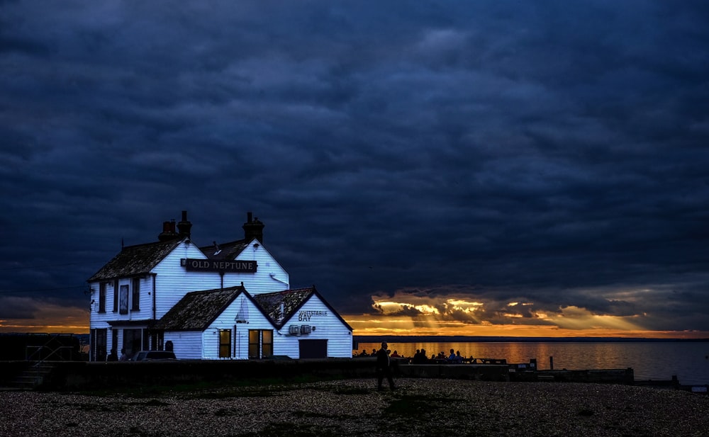 white and brown building near body of water under thick gray clouds during golden hour photo