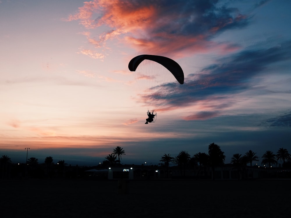 silhouette of man parachuting under gray sky