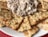 A plate filled with seasoned crackers arranged around a generous serving of a creamy tuna salad mixture. The tuna salad contains visible chunks of vegetables and possibly herbs.