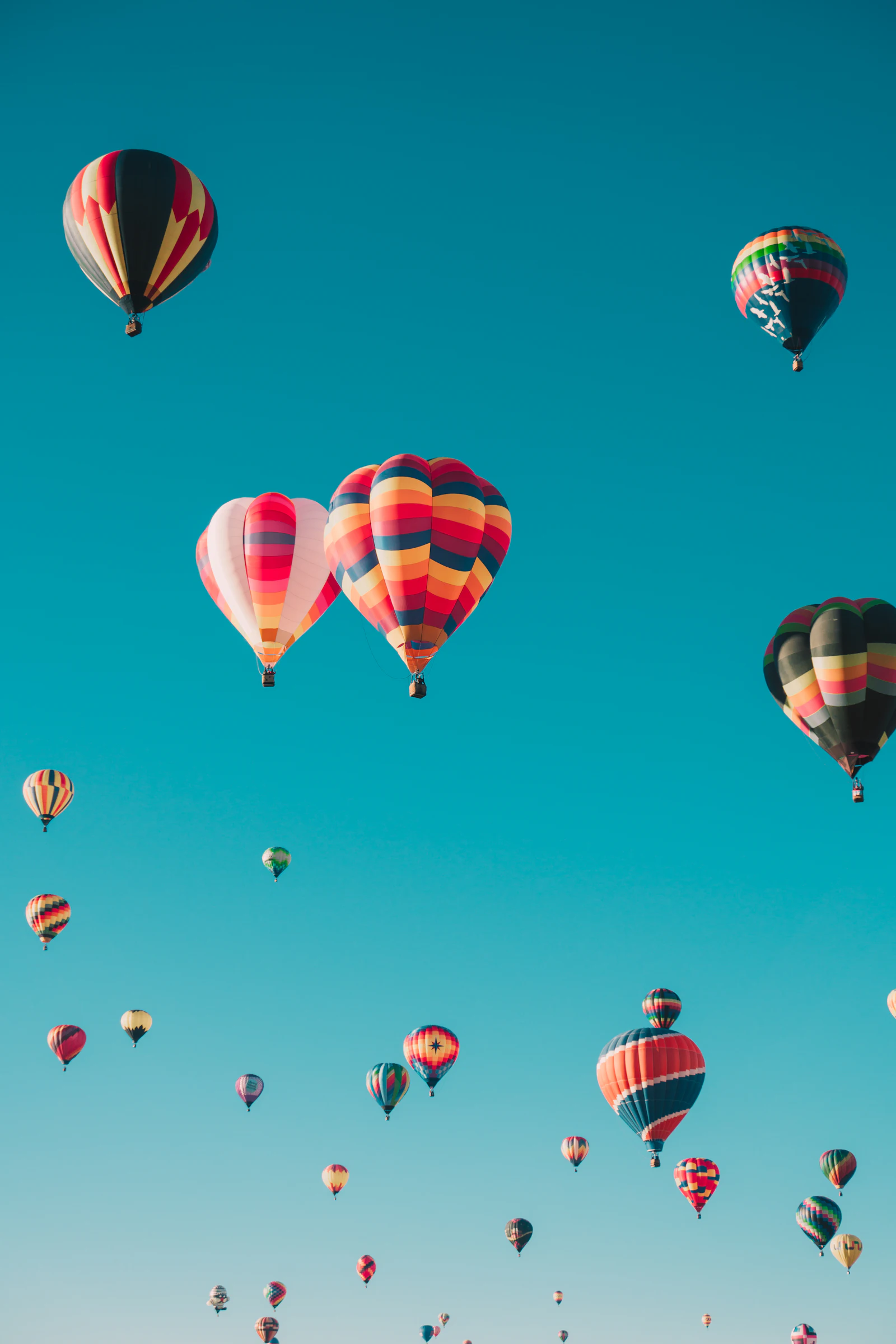 Mange fargerike varmluftballonger mot blå himmel