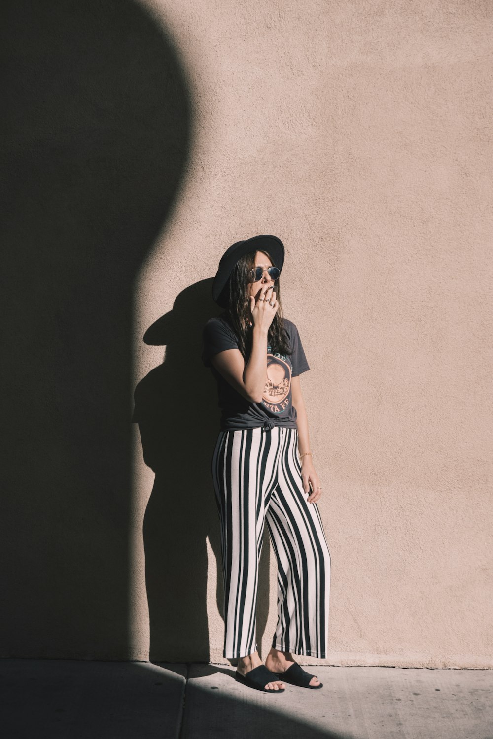 woman leaning on pink wall during daytime