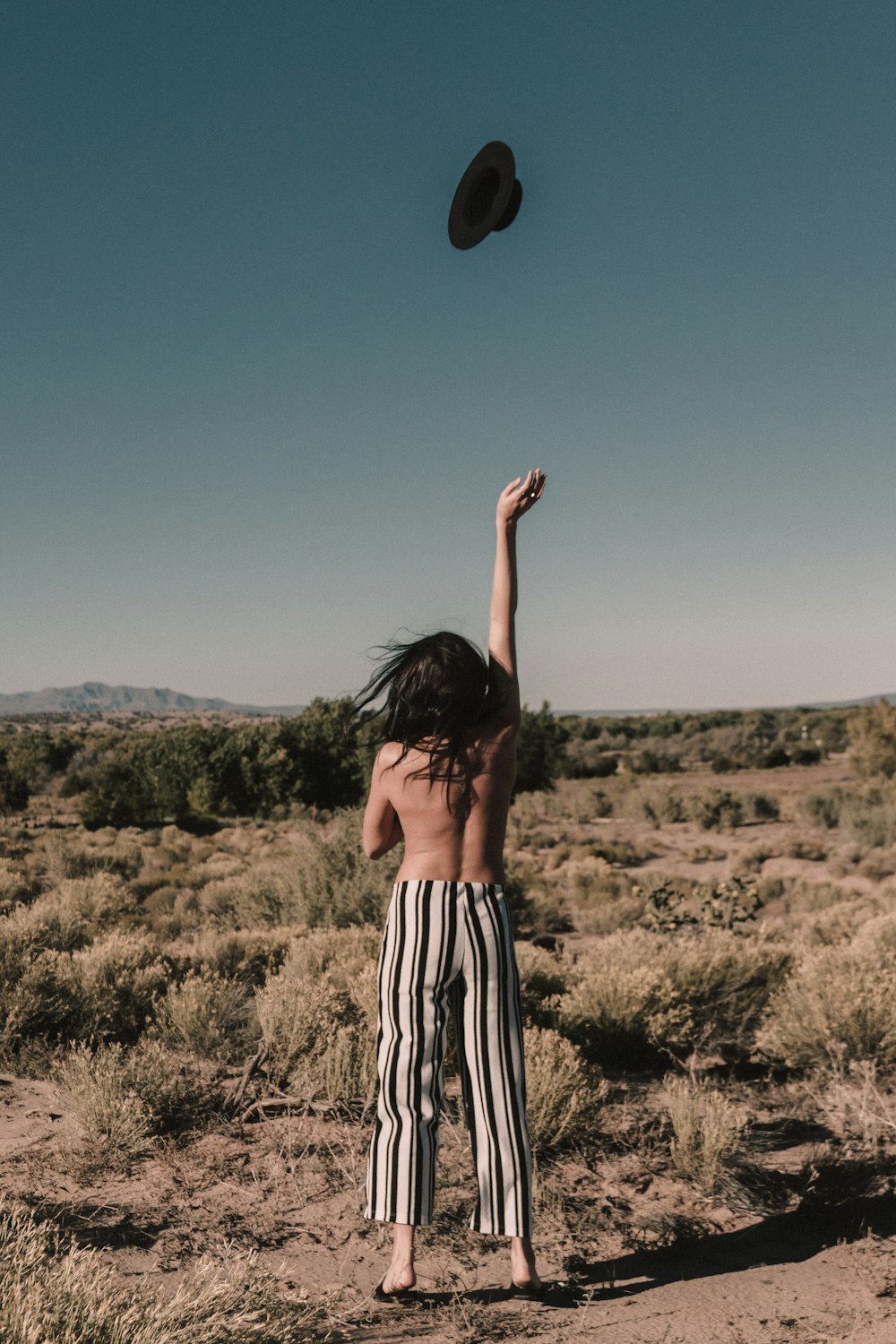 topless person throwing black hat