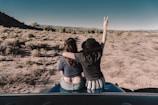 two woman sitting on car hood
