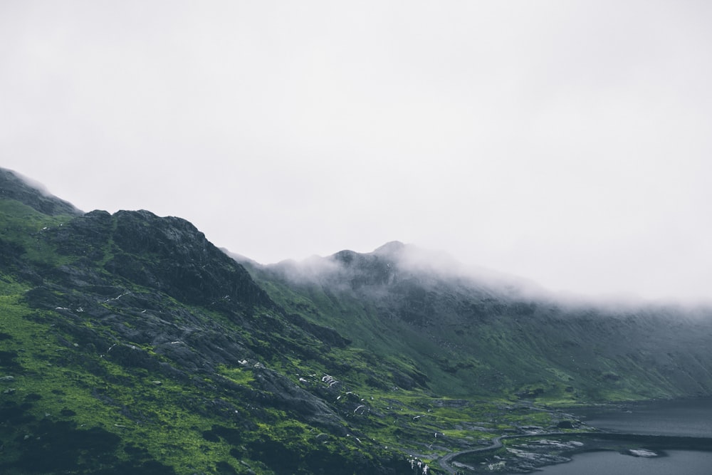 green mountain near body under white sky during daytime