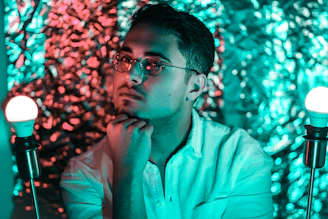 Close-up of a thoughtful man with glasses jotting notes, illuminated by cool blue lighting creating a calm tech-inspired atmosphere