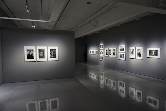 A sleek black and white gallery interior showcasing large contemporary artworks under soft lighting.