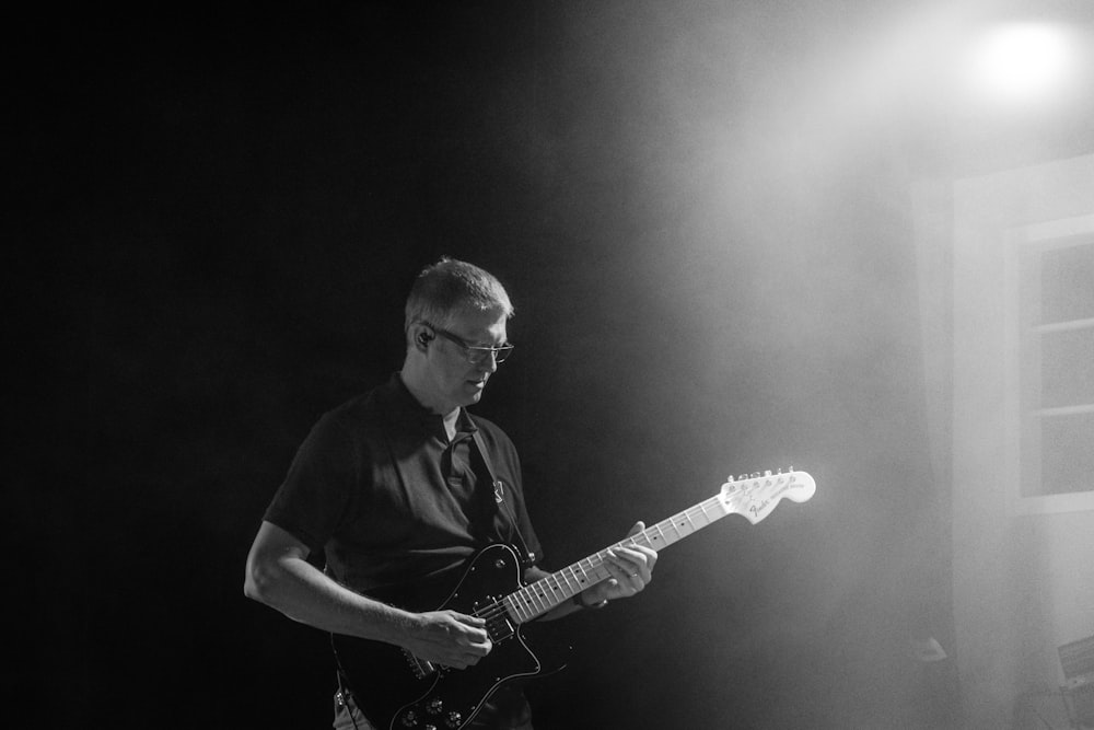 grayscale photo of man playing guitar