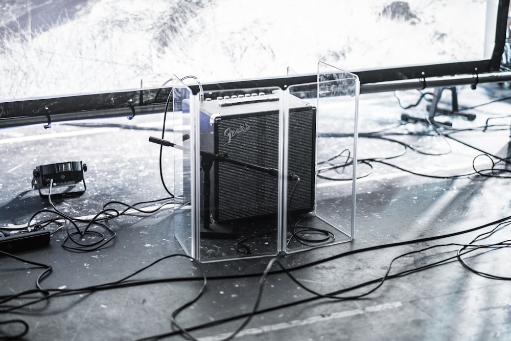 Amplificateur de guitare Fender carré gris et noir entouré d’un panneau en verre transparent sur le dessus de la scène à côté de l’éclairage de la scène
