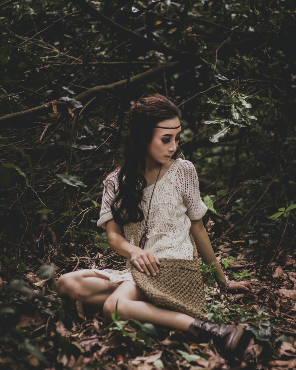 sitting woman on dried leaves surrounded with plants photo