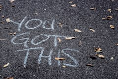 A photo of the asphalt with "You Got This" written in chalk.