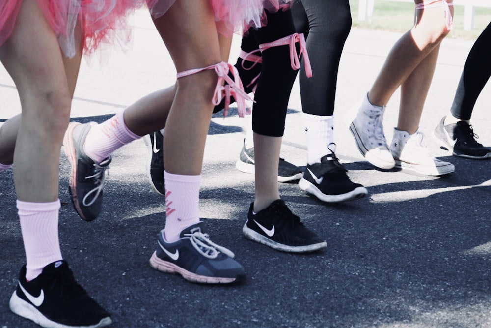 personne portant plusieurs paires de chaussures de course Nike debout sur un sol en béton gris pendant la journée