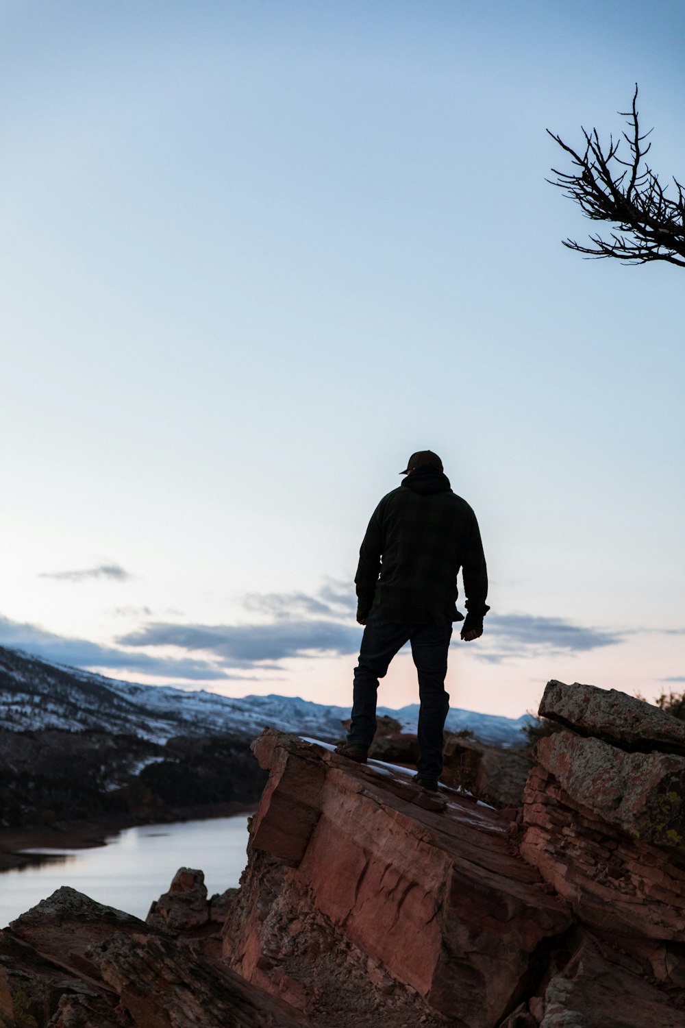 man standing on rock edge overlooking valley