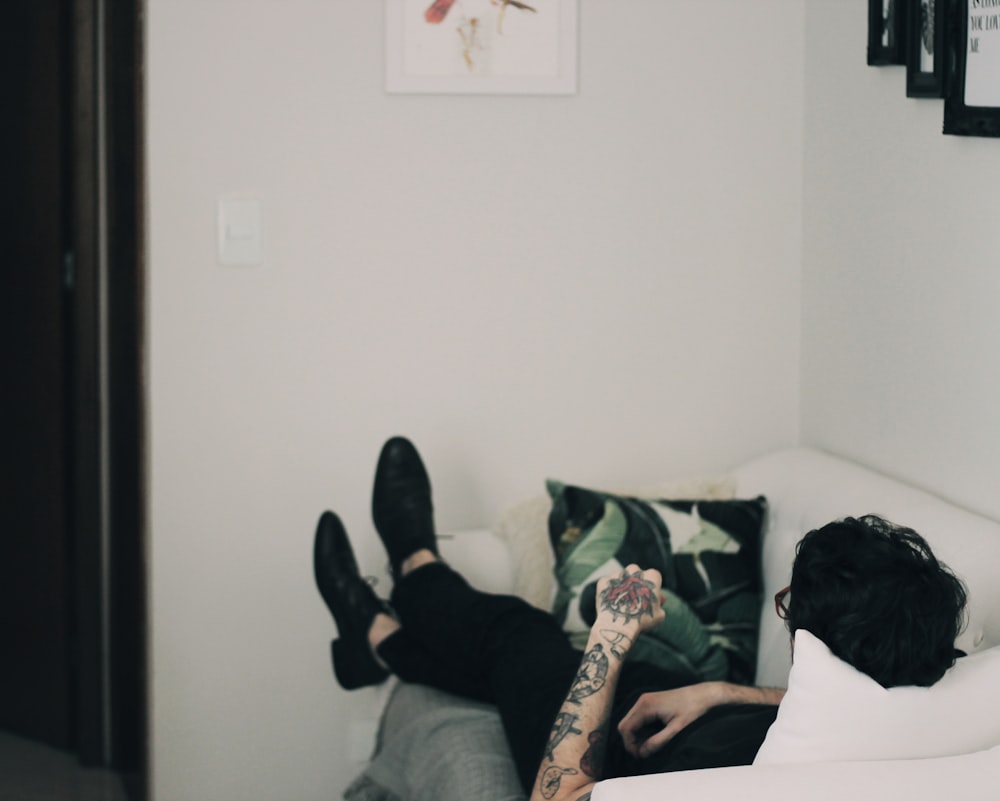 man lying on white sofa