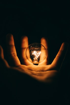 clear glass bulb on human palm