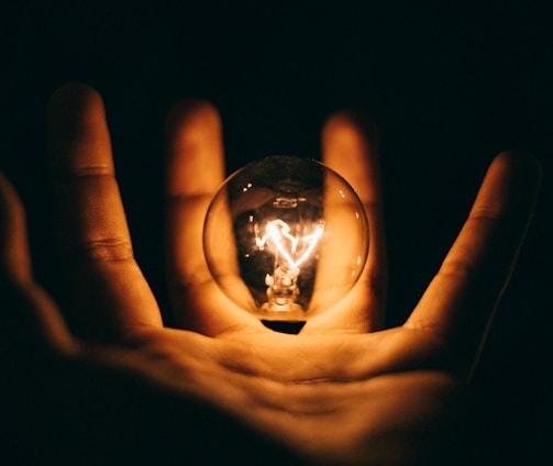 clear glass bulb on human palm