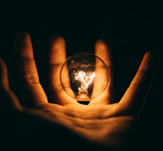 clear glass bulb on human palm