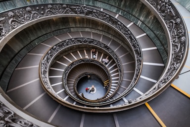 architectural photography,how to photograph l’escalier de bramante est un escalier à double hélice des musées du vatican. attribué à tort à donato bramante, cet escalier fut dessiné par giuseppe momo en 1932, inspiré par un plus ancien effectivement dessiné par bramante. cet escalier est une double hélice, c’est-à-dire qu’il comporte deux escaliers, un pour monter, et un pour descendre. ainsi personne ne se croise en sens inverse.
 
 assemblage dans photoshop de 5 photos (pour supprimer un maximum de personnes) prises à main levée (trépied interdit) au fujifilm x-t2 et xf 10-24mm à 10mm, f/9.0, 1/40s et 1600 iso.; aerial view of spiral stairway building