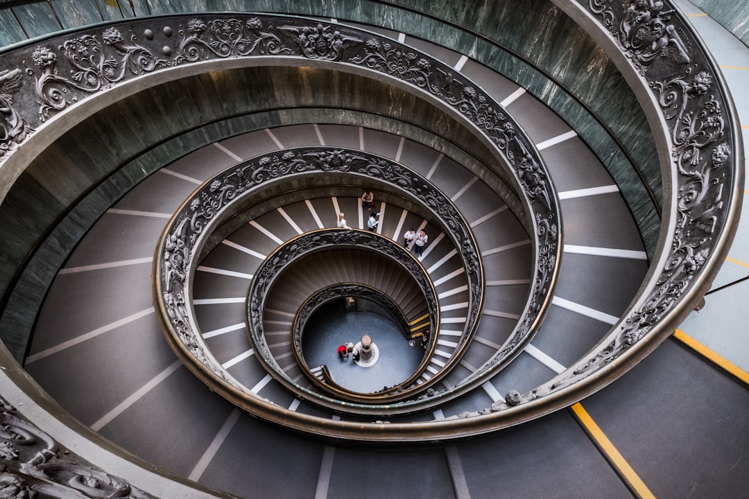 aerial view of spiral stairway building, L’escalier de Bramante est un escalier à double hélice des musées du Vatican. Attribué à tort à Donato Bramante, cet escalier fut dessiné par Giuseppe Momo en 1932, inspiré par un plus ancien effectivement dessiné par Bramante. Cet escalier est une double hélice, c’est-à-dire qu’il comporte deux escaliers, un pour monter, et un pour descendre. Ainsi personne ne se croise en sens inverse.</p></figure><p>Assemblage dans Photoshop de 5 photos (pour supprimer un maximum de personnes) prises à main levée (trépied interdit) au Fujifilm X-T2 et XF 10-24mm à 10mm, f/9.0, 1/40s et 1600 ISO.