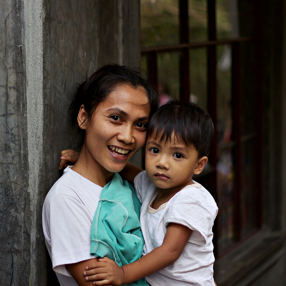 woman carrying a boy near metal frame