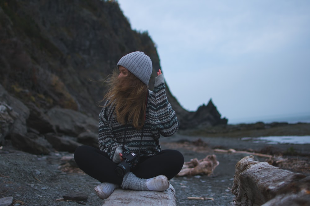 woman wearing gray shirt sitting near seashore