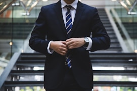 A person in office wear, buttoning his coat