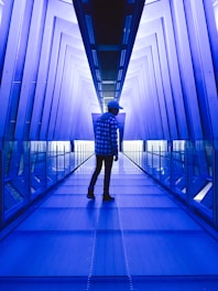 man standing between walls with blue lights