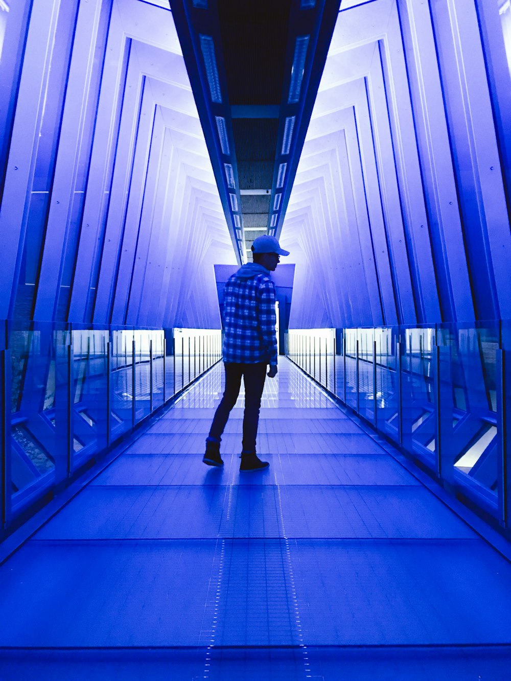 man standing between walls with blue lights