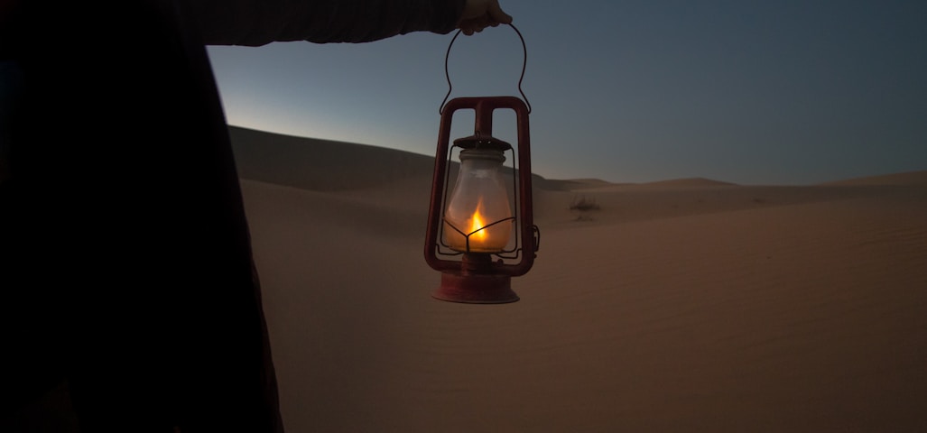 person holding red kerosene lantern