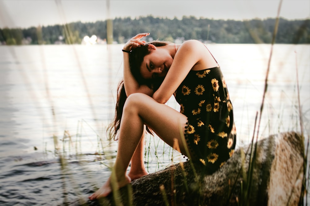 woman sitting on rock near water