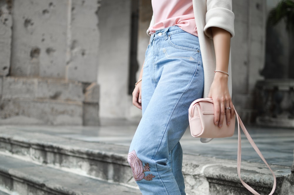 donne che tengono borsa a tracolla in pelle rosa sulla scala