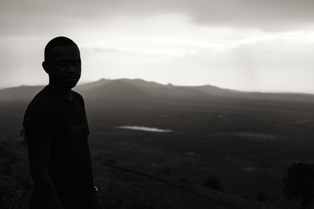 boy standing on bare hill during foggy day