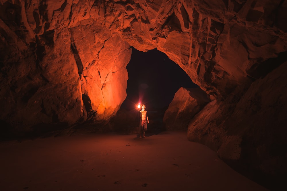 man holding red light flare inside cave