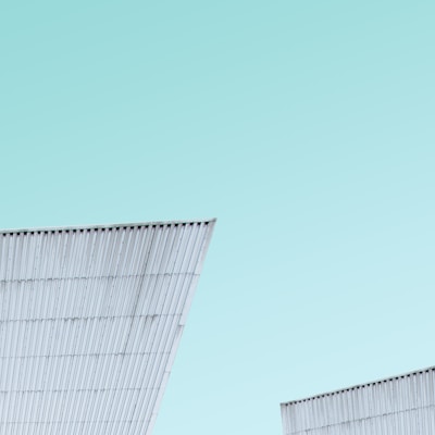 A sleek, modern modular steel home with large windows set against a clear blue sky.