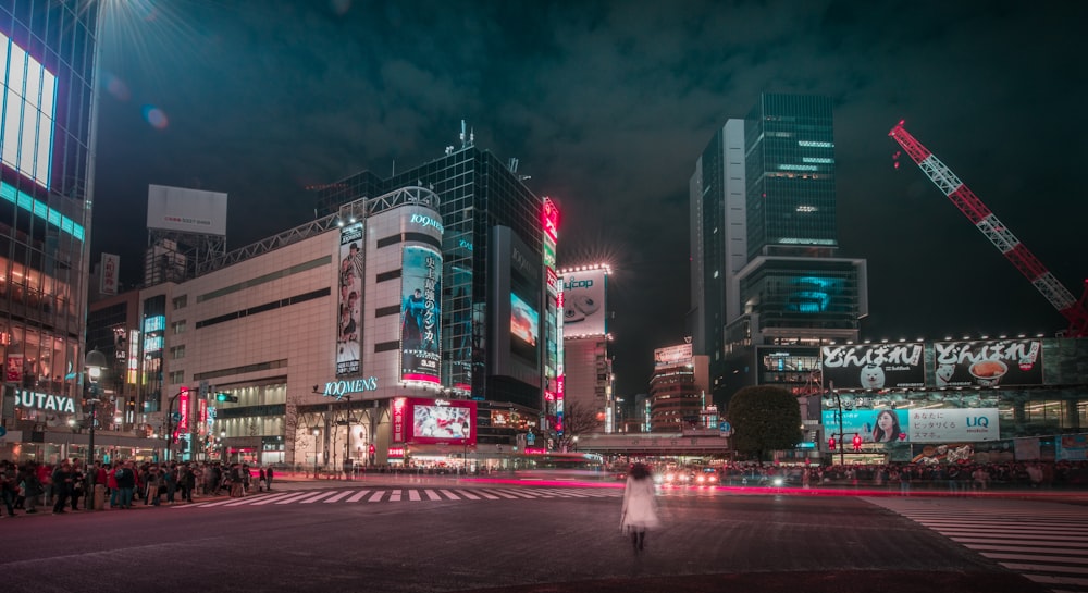 timelapse photography of person walking outside pedestrian lane overlooking buildings at night time