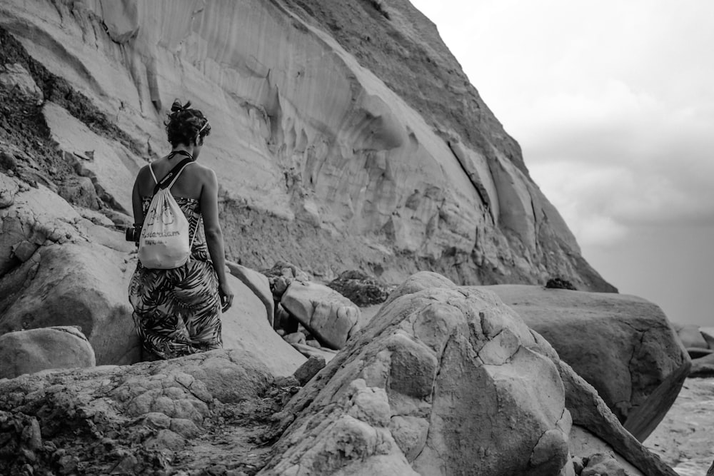 grayscale photography of person walking along outcrop