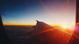 A sunset view from an airplane window showing clouds and a golden sky