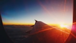 A sunrise view from an airplane window showing clouds and a golden sky