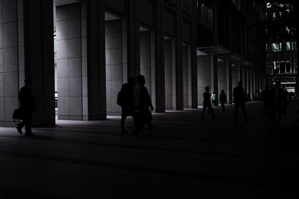 a group of people walking down a street next to tall buildings