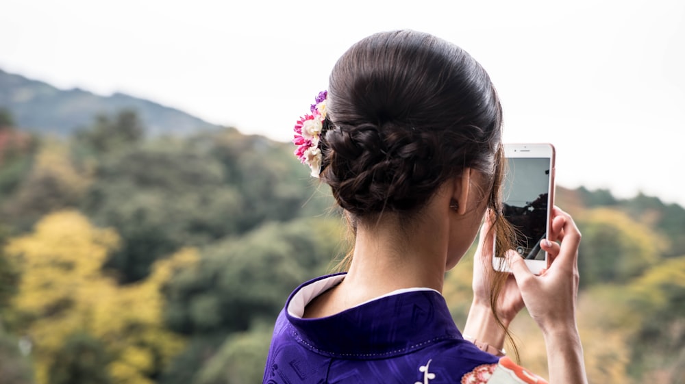 woman taking photo beside trees