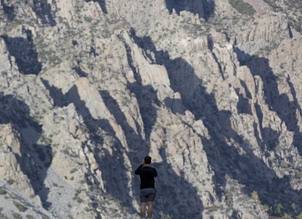 man standing in front gray mountain