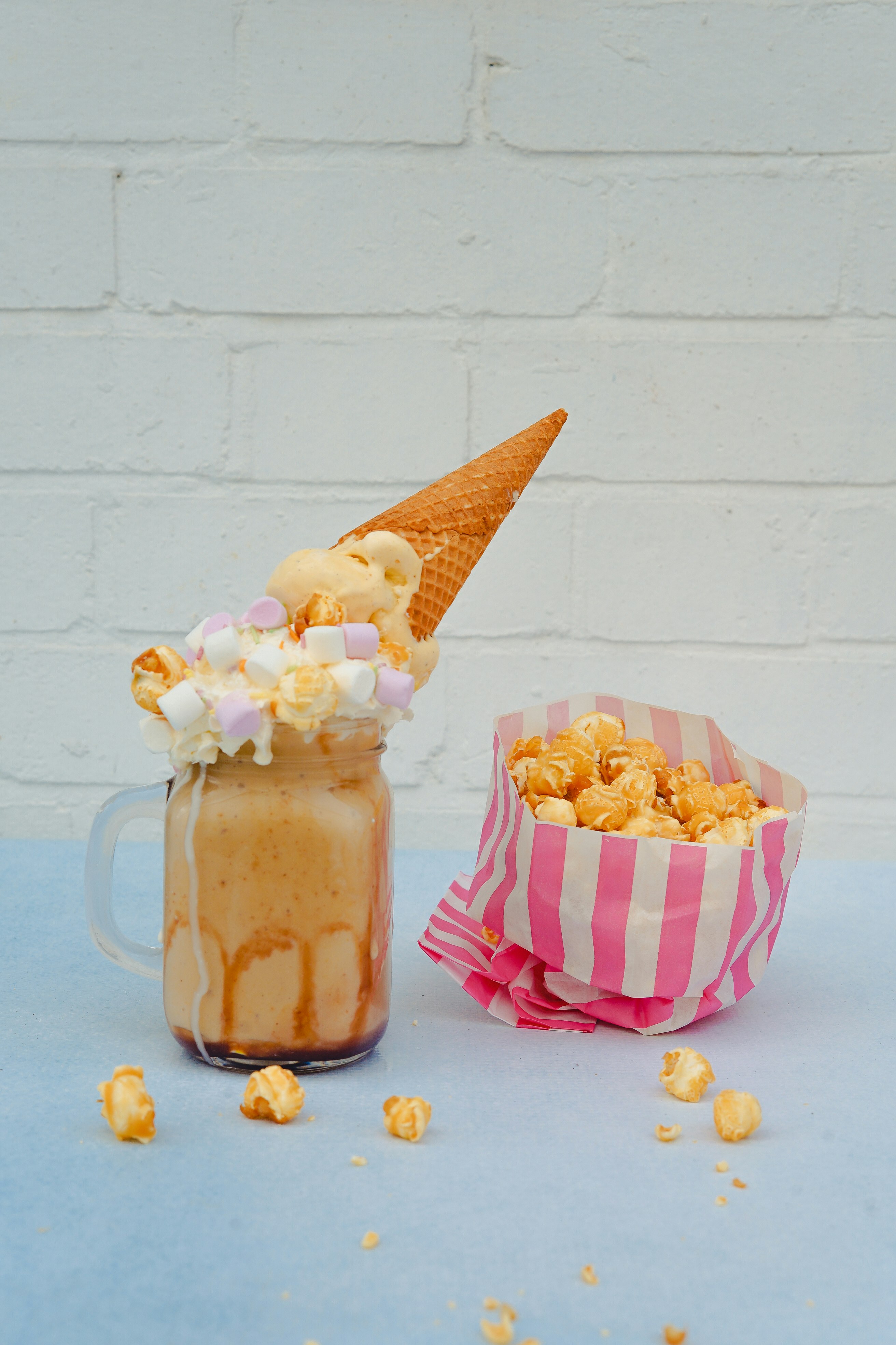 ice cream in a jar with marshmallow and cone and a pack of popcorn