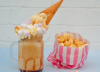 ice cream in a jar with marshmallow and cone and a pack of popcorn